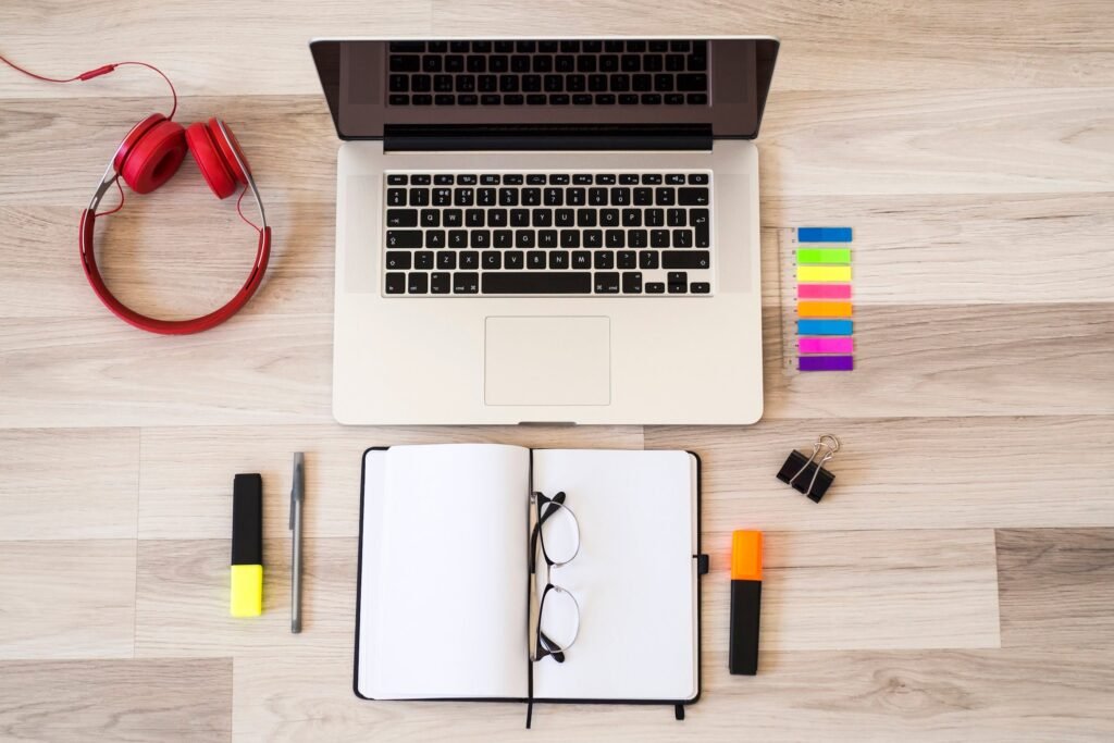 laptop near eyeglasses notepad headphones floor