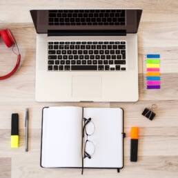 laptop near eyeglasses notepad headphones floor