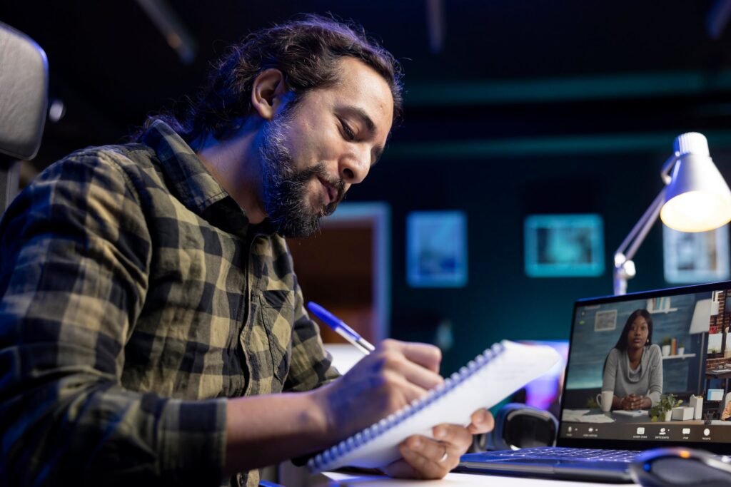 man writing book while video call