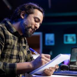 man writing book while video call