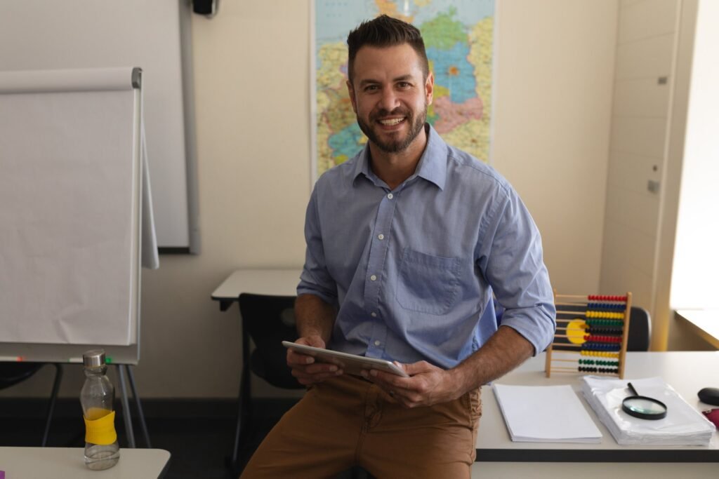 school teacher looking camera sitting desk classroom