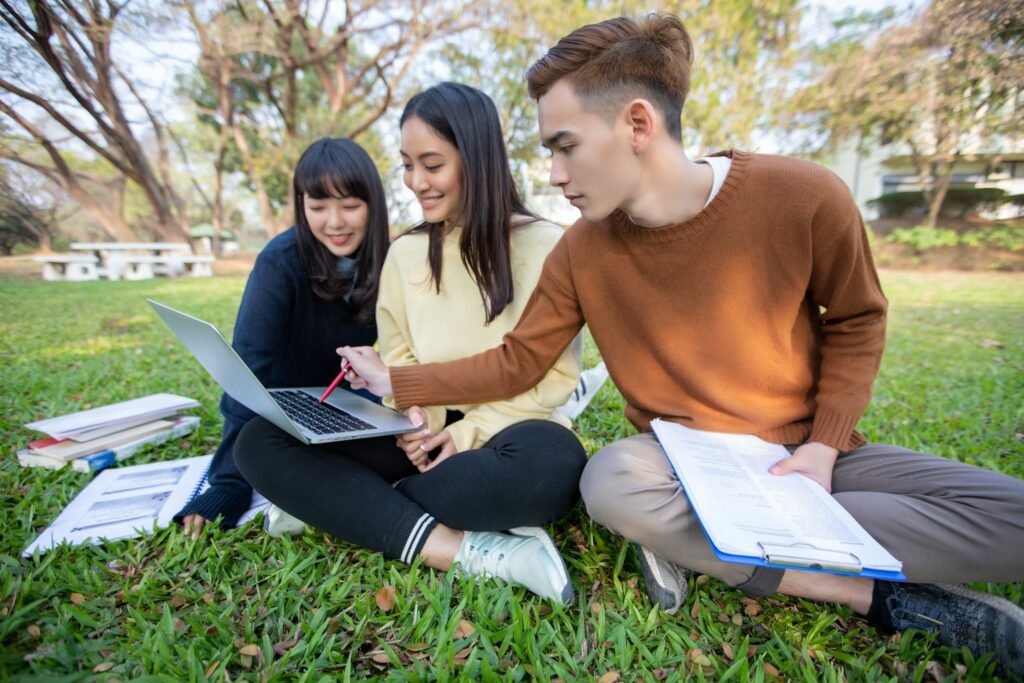students studying while sitting grass park
